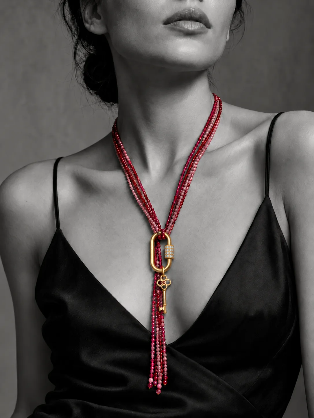 Black and white portrait with ruby strands worn at the front and a small gold key charm